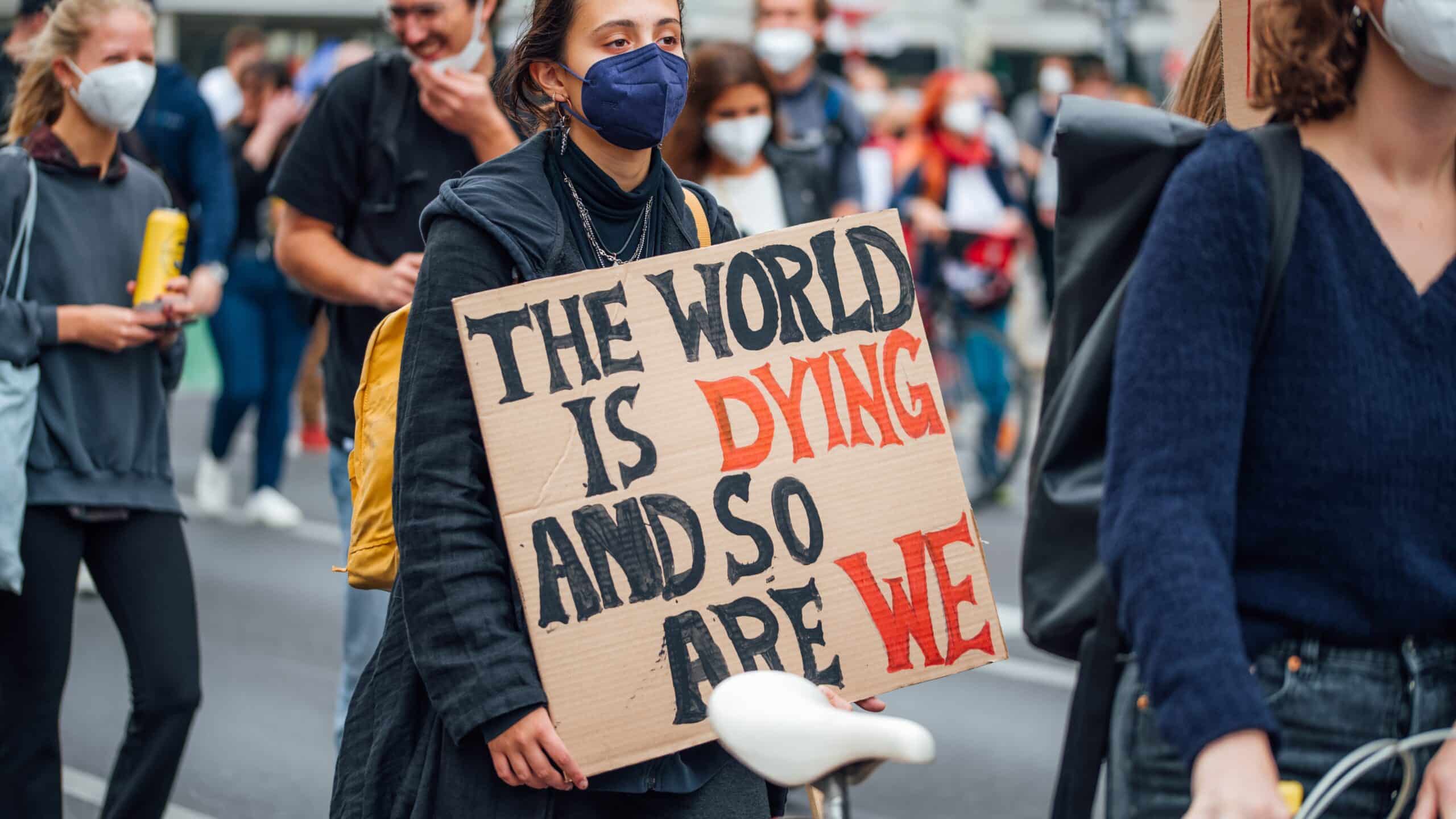 Climate change activist holding a banner with the message "The world is dying and so are we"